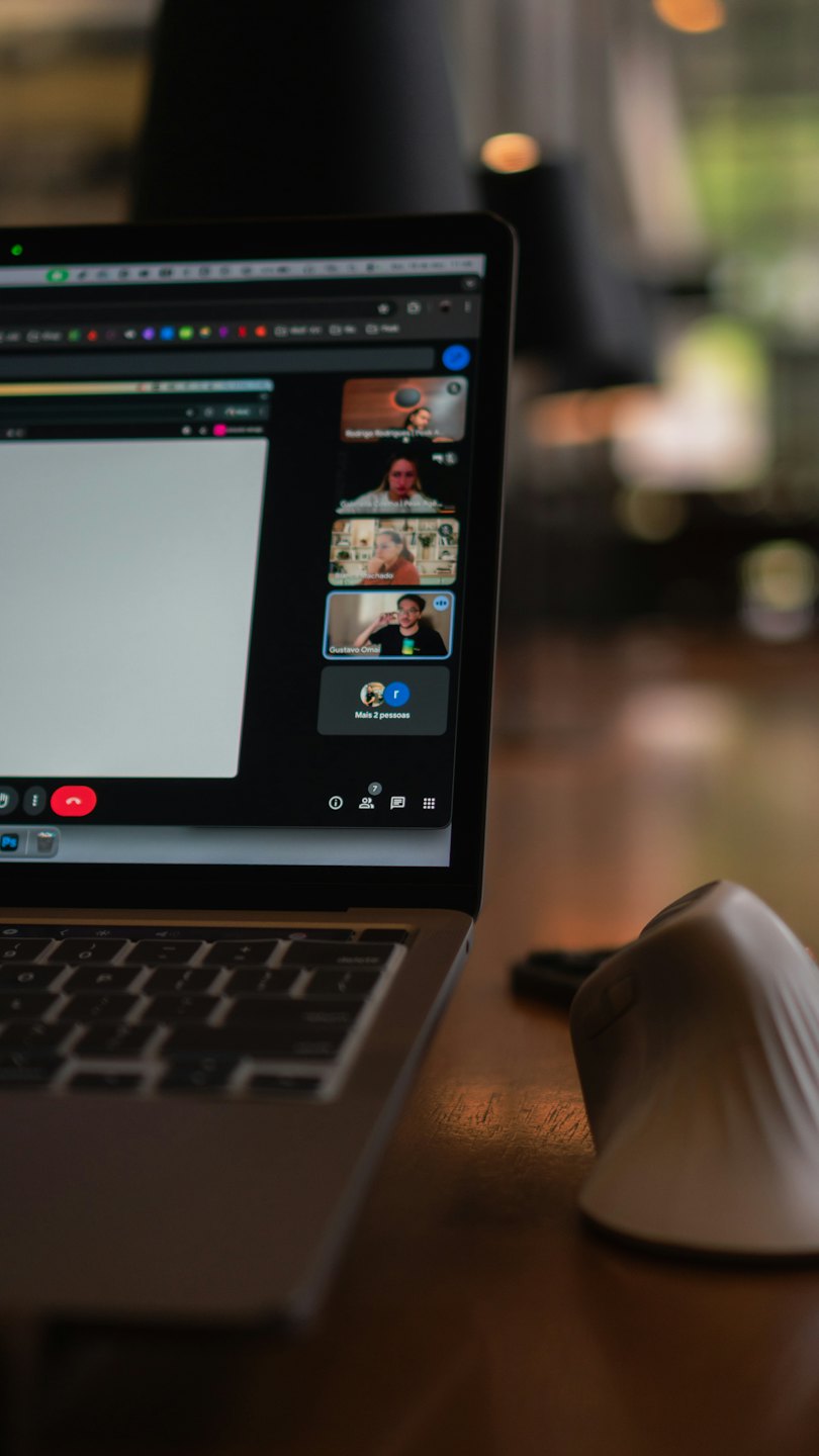 Laptop displaying video conference on a wooden desk.